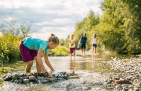 Ein Kind spielt mit Wasser und Steinen in einem Bach