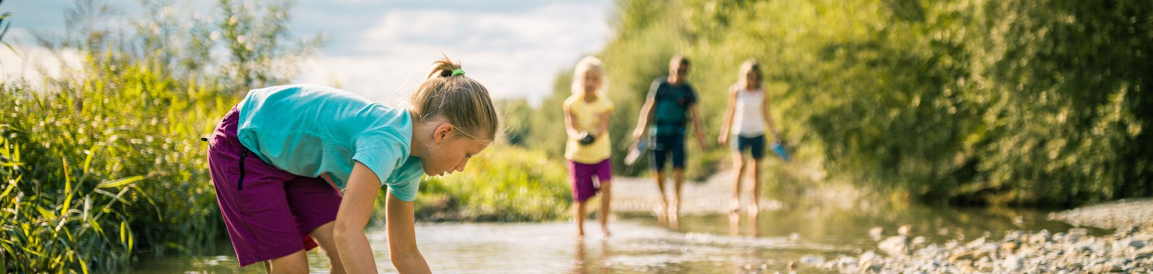 Ein Kind spielt mit Wasser und Steinen in einem Bach